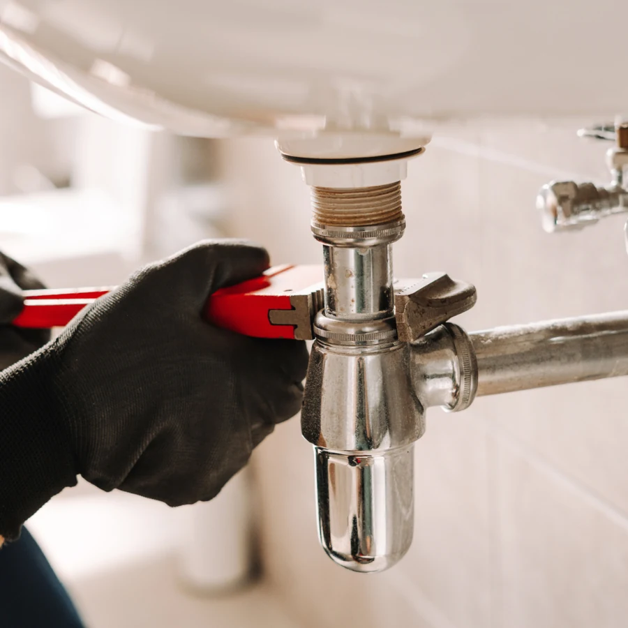 Plumber tightening a sink drain connection with a wrench